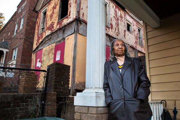 McCullum stands on her porch with the offending house in the background