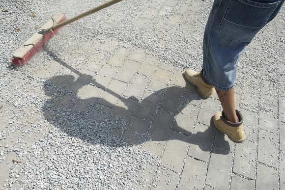 Spreading gravel to finish up the permeable paver installation