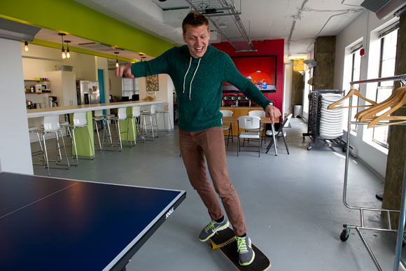 Creative director Zach Goodwin skateboards through the office 