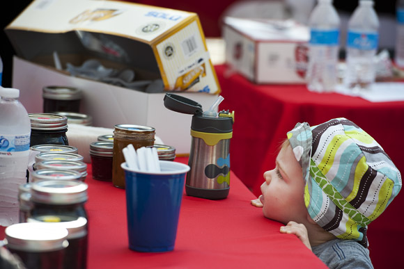 Eighteen-month-old Caden Kiraly peeks up at the table where his mother, Stacia, is judging jam at the DC State Fair
