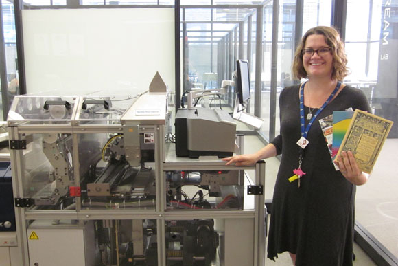 Digital commons librarian Emily Graves poses in front the Espresso Book Machine with copies of self published books created at the library